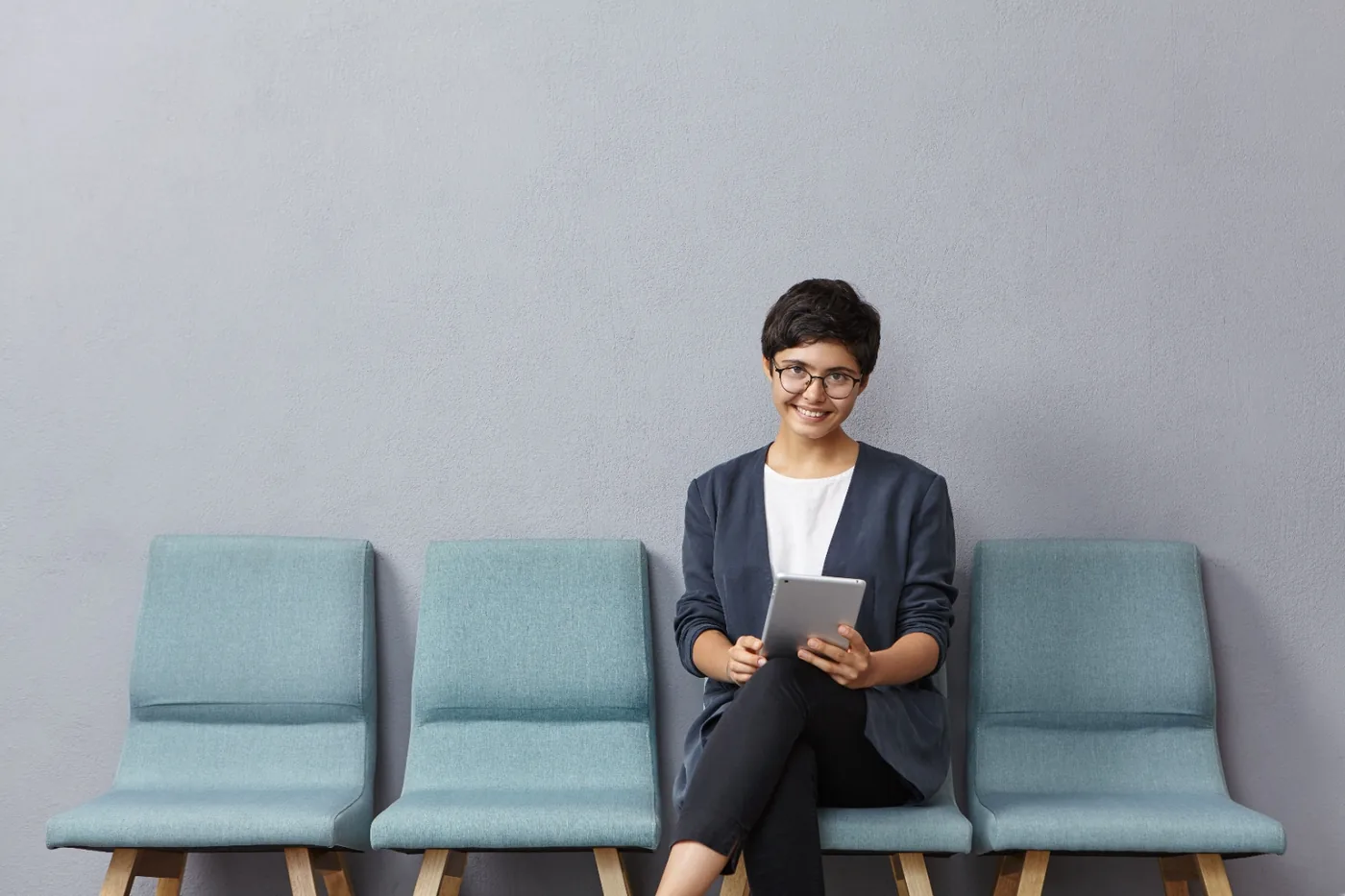 Smiling professional seated with a tablet before an interview